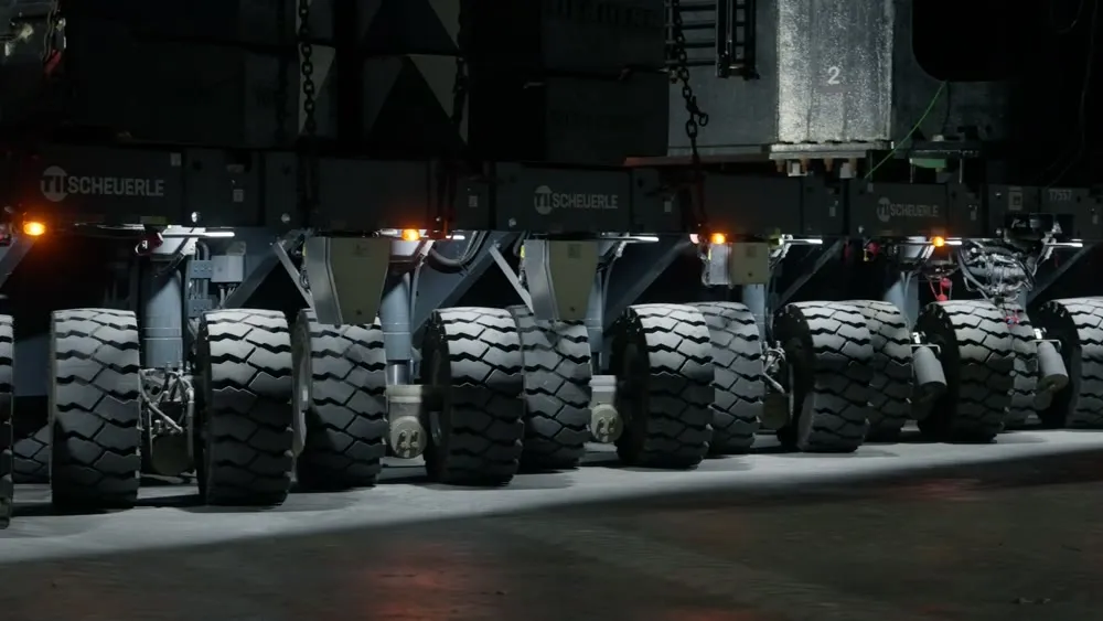 A multi-wheel transporter carrying Starship hardware at night